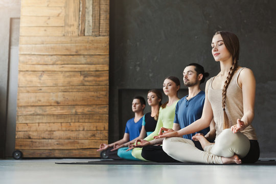 Young women and men in yoga class, relax meditation pose