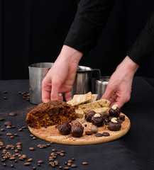 women's hands hold a tray with chocolate truffles, a piece of pie and slices of bread
