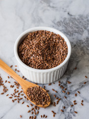 Flax seeds in white ramekin on marble board