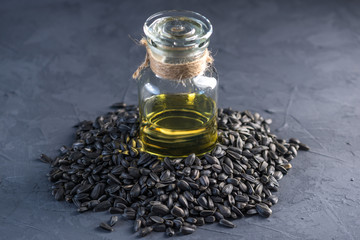 Sunflower seeds in a pile and golden oil in a glass bottle on the table. Healthy diet with vegetable fats.