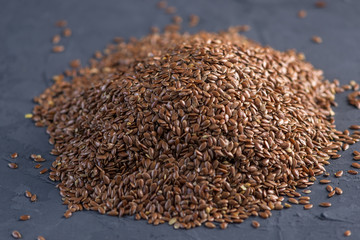 Flax seeds in a pile on a dark background. Top view. Healthy diet with omega 3 fatty acids.