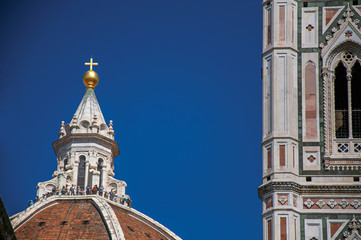 Fototapeta premium Close-up of people on the dome of the Santa Maria del Fiore Cathedral and Giotto's Campanile (bell tower). In Florence, the famous and amazing capital of the Italian Renaissance. Tuscany region