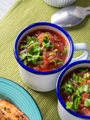 Russian beetroot soup borscht in enamel mugs on green cloth