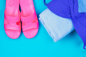 Slippers, swimsuit, towel on a blue pastel background. Rest, travel. Top view. Copy space. Flat lay.