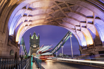 Die Tower Bridge in London am Abend mit vorbeifahrendem, rotem Doppeldecker Bus