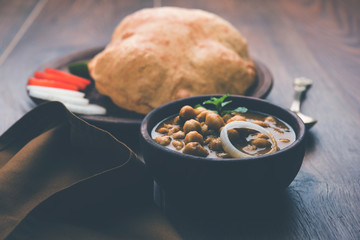 Chole Bhature or Chick pea curry and Fried  Puri served in terracotta crockery over white background. selective focus