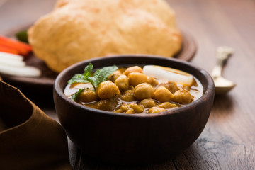 Chole Bhature or Chick pea curry and Fried  Puri served in terracotta crockery over white background. selective focus