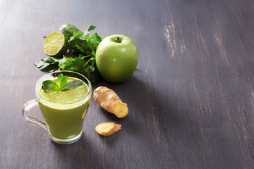 Fresh green smoothies with parsley, ginger, apple, lime and mint in a glass on a black wooden table with low back light. Healthy food. Copy space