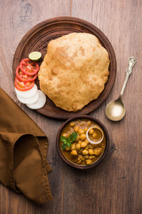 Chole Bhature or Chick pea curry and Fried  Puri served in terracotta crockery over white background. selective focus