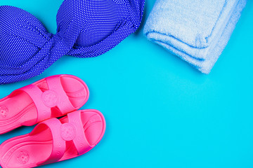 Slippers, swimsuit, towel on a blue pastel background. Rest, travel. Top view. Copy space. Flat lay.