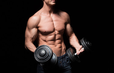 Naklejka na ściany i meble Handsome power athletic man with dumbbell confidently looking forward. Strong bodybuilder with six pack, perfect abs, shoulders, biceps, triceps and chest. Strength and motivation