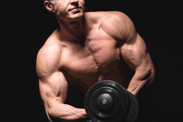 Fototapeta na wymiar Handsome power athletic man with dumbbell confidently looking forward. Strong bodybuilder with six pack, perfect abs, shoulders, biceps, triceps and chest. Strength and motivation