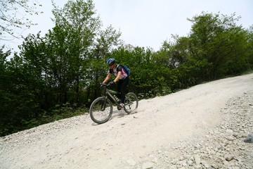 Young woman down on a bike on a dirt road, Sochi