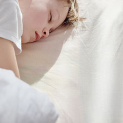 Portrait of cute young boy sweetly sleeping in bed