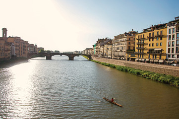 Overview of rower on the river Arno, bridge and buildings at sunset. In the city of Florence, the famous and amazing capital of the Italian Renaissance. Located in the Tuscany region