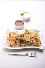 Egg Biryani - Basmati rice cooked with masala roasted eggs and spices and served with yogurt, selective focus