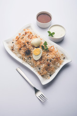 Egg Biryani - Basmati rice cooked with masala roasted eggs and spices and served with yogurt, selective focus
