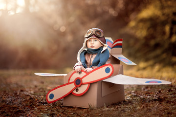 the boy plays in an airplane made of cardboard box and dreams of becoming a pilot