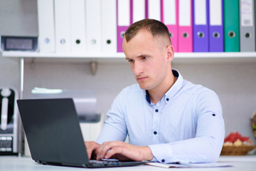 Portrait of a young male manager at the office with a laptop