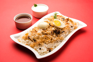 Egg Biryani - Basmati rice cooked with masala roasted eggs and spices and served with yogurt, selective focus