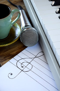 Synthesizer, microphone and treble clef on white paper