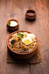 Egg Biryani - Basmati rice cooked with masala roasted eggs and spices and served with yogurt, selective focus