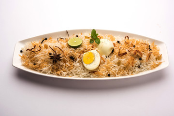 Egg Biryani - Basmati rice cooked with masala roasted eggs and spices and served with yogurt, selective focus