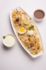 Egg Biryani - Basmati rice cooked with masala roasted eggs and spices and served with yogurt, selective focus