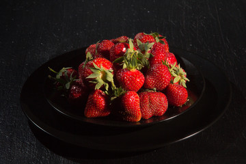 Fresh ripe strawberry in a black plate