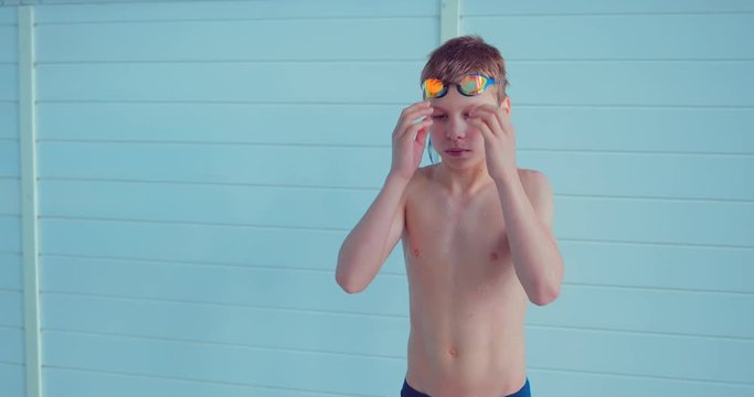 Professional swimmer teenager wears goggles before swimming training in the pool