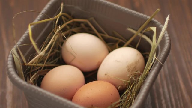A female hand is laying an egg on the basket with eggs