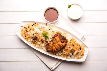 Authentic Fish Biryani served in a white plate over white background, selective focus