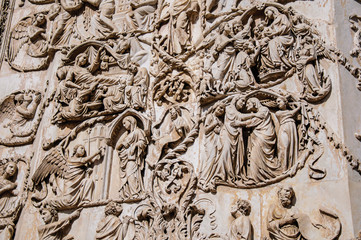 Fototapeta na wymiar Close-up of the opulent and elaborated embossed sculptures in the Orvieto Cathedral (Duomo) on a sunny day in Orvieto, a pleasant and well preserved medieval town. Located in Umbria, central Italy
