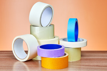 Multi colored multipurpose adhesive tape rolls lie on table.