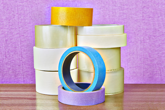 Stacked rolls of scotch tape is various purposes, purple background.