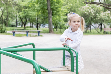 Little girl spins the carousel to ride at the playground