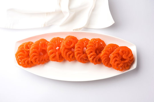 Indian sweet Imarti or Jalebi served in white ceramic plate over white background