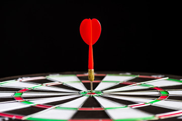 Fototapeta premium Close up shot red darts arrows in the target center on black background. Business target or goal success and winner concept.