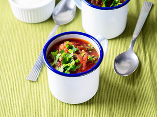 Russian beetroot soup borscht in enamel mugs on green cloth