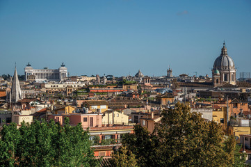 Fototapeta na wymiar Overview of trees, cathedrals domes and roofs of buildings in the sunset of Rome, the incredible city of the Ancient Era, known as 