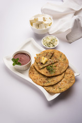 Stuffed Paneer Paratha with melting butter, served with fresh Cottage Cheese cubes and tomato ketchup. Selective focus