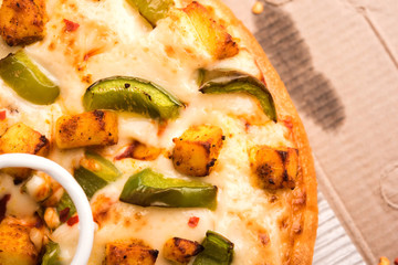 Paneer Pizza is an indian version of Italian dish topped with Cottage Cheese, served in a plate with white sauce. selective focus