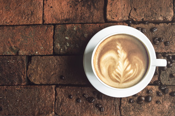 A cup of hot coffee ,latte art on bricks in morning, Coffee with a pattern of milk in white cup.