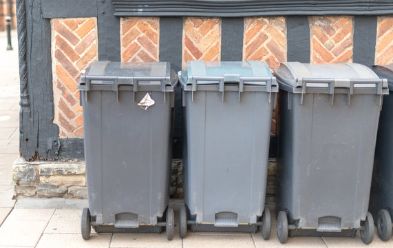 wheelie bins against Tudor wall in UK tourist town Stratford upon Avon awaiting collection