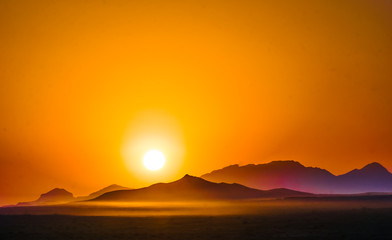 Orange sunset over the mountains in the desert