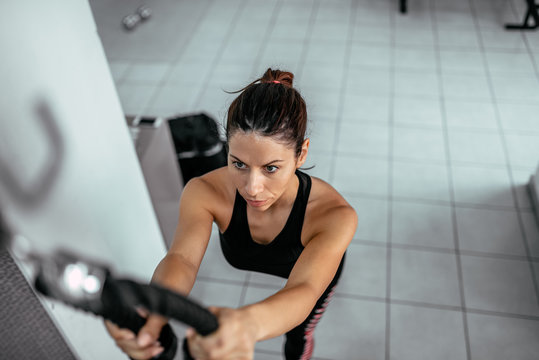 High view angle image of woman exercising on pull down machine at gym.
