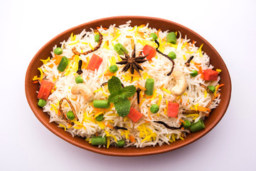 Indian Vegetable Pulav or Biryani made using Basmati Rice, served in a ceramic bowl. selective focus
