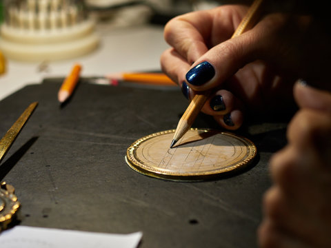 The engraver places a marking on the medal over the paste.