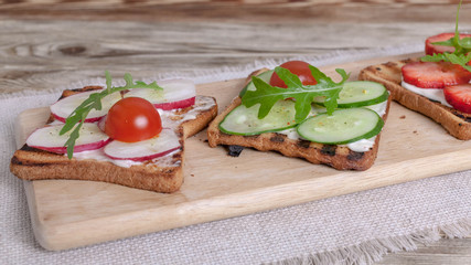 Sandwiches with cream cheese, radish, fresh cucumber, strawberries and arugula. Banner