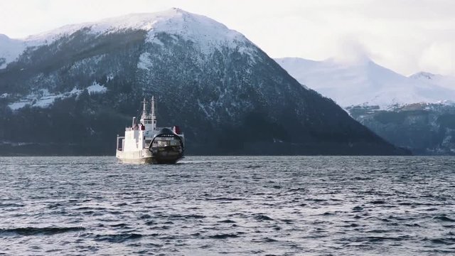 Ferry on the fjord with snow mountains, near volda (norway)